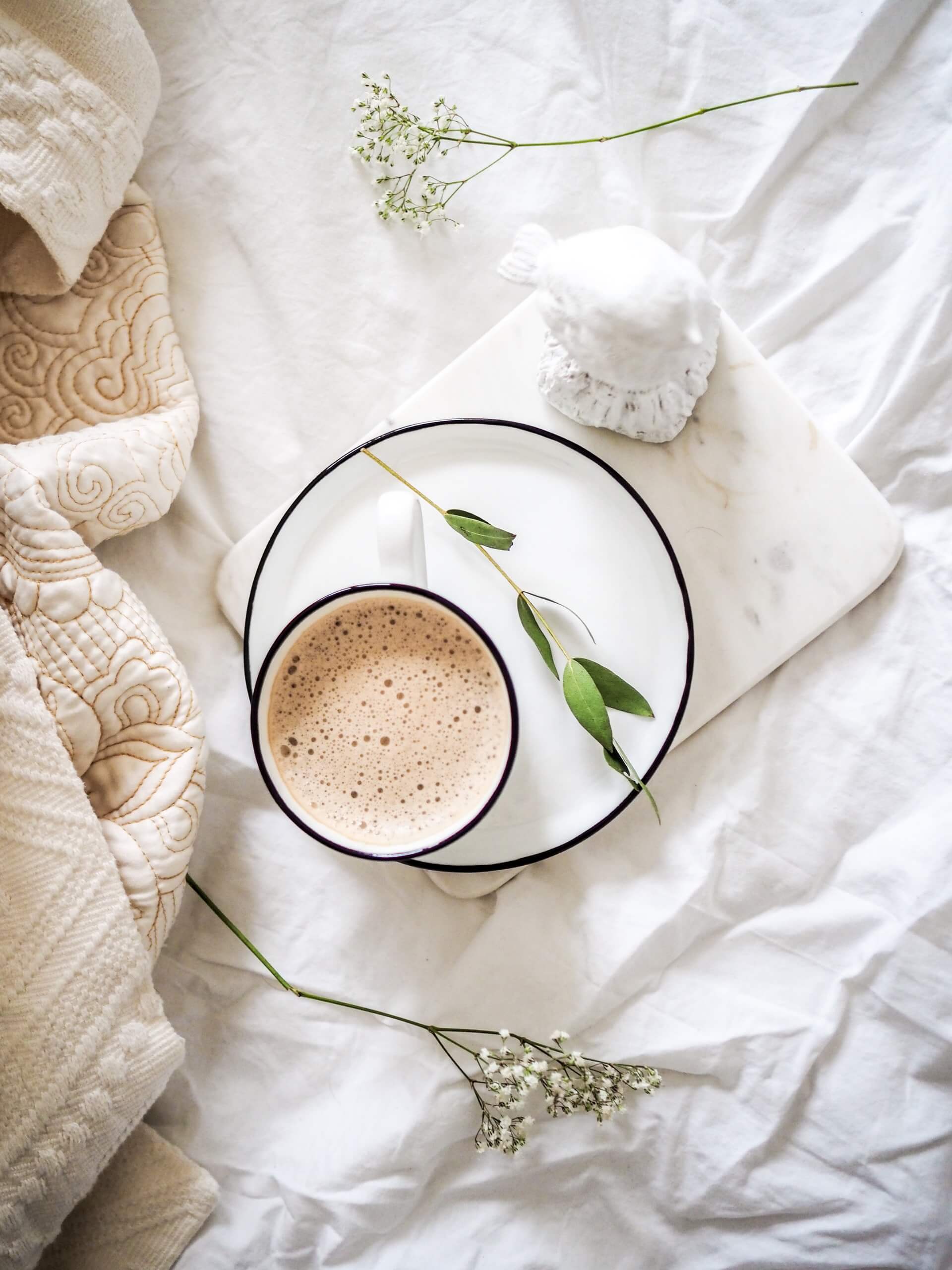 foto of a cup and book on the bed